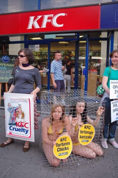 Animal activists Jodi Ruckley (left) and Karolina Kostrzzewa-Colwill (right) in a cage during a protest for PETA's Campaign Against KFC in front of a KFC restaurant in Warsaw, Poland.